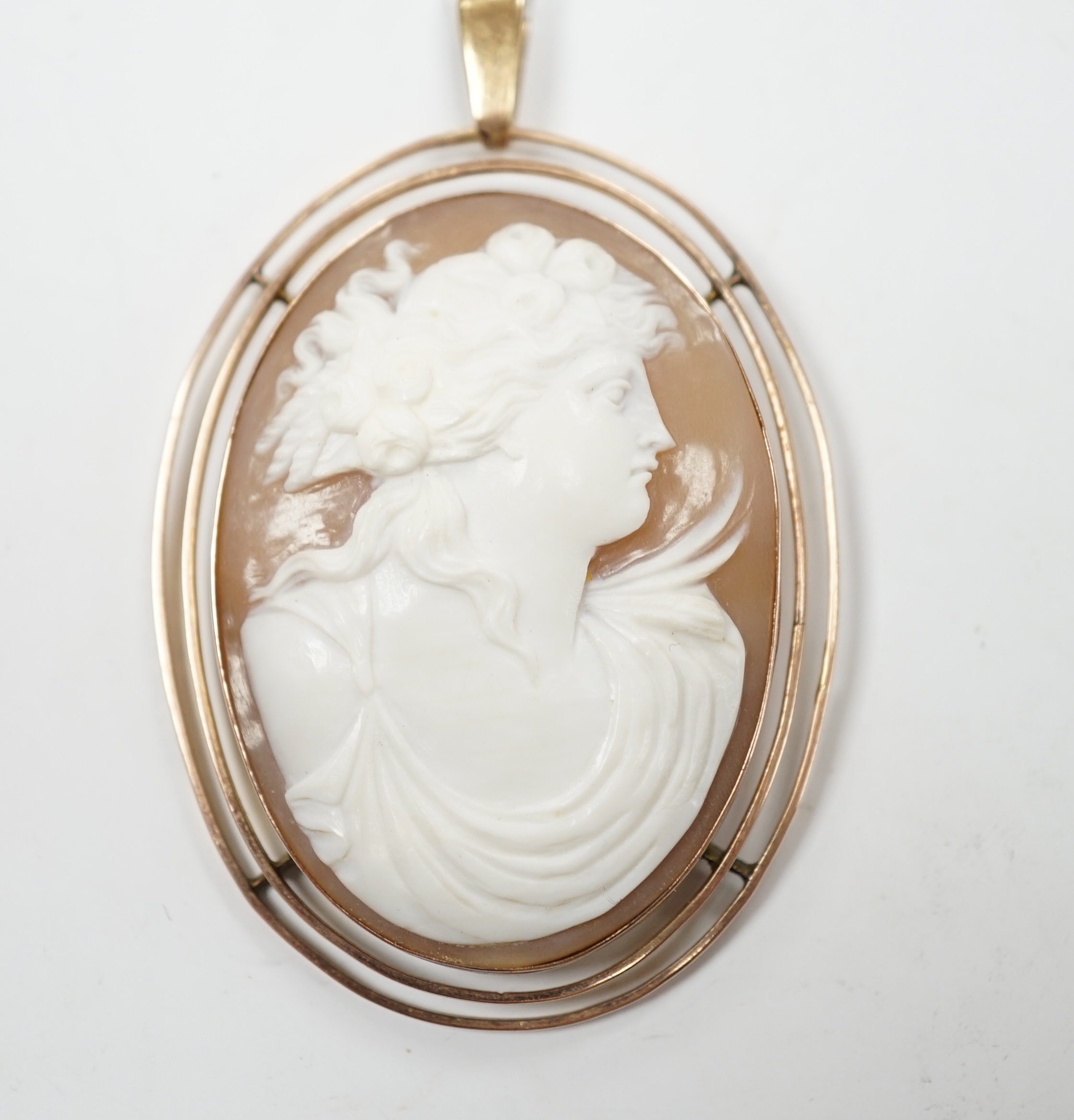 An early 20th century 9ct mounted oval cameo shell pendant, carved with the bust of a lady to sinister, overall 83mm, gross weight 13.2 grams.